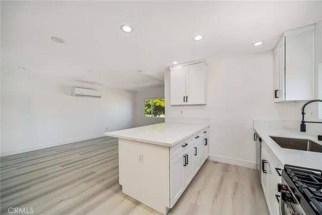a kitchen with a sink a stove cabinets and wooden floor