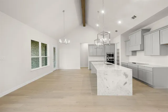 a large kitchen with kitchen island white cabinets and stainless steel appliances