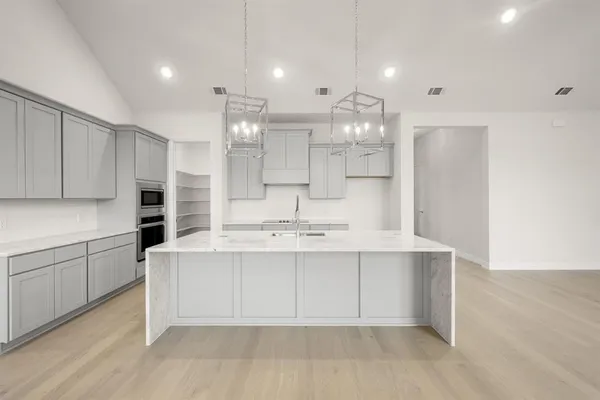 a large white kitchen with a sink and cabinets