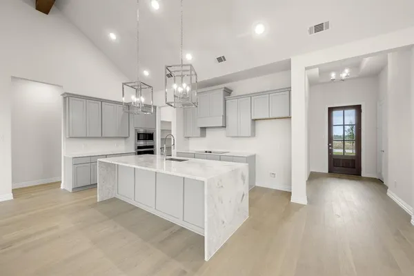a large white kitchen with a large counter top appliances and cabinets