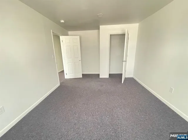 a view of an empty room with closet and a window