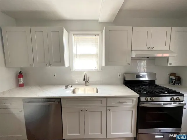 a kitchen with white cabinets and appliances