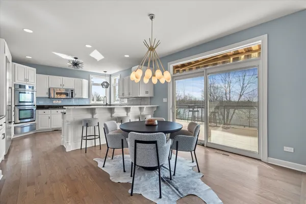 a kitchen with stainless steel appliances a table chairs in it and wooden floors