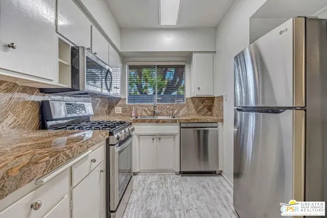 a kitchen with stainless steel appliances granite countertop a refrigerator stove and sink