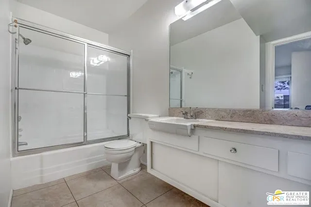 a bathroom with a granite countertop sink a toilet and a mirror