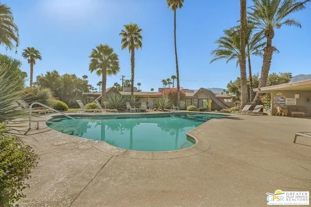 a view of a house with a yard and palm trees