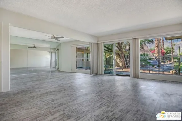 a view of a big room with wooden floor and windows