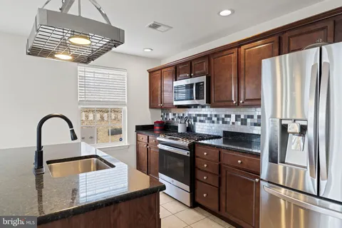 a kitchen with stainless steel appliances granite countertop a refrigerator a stove a sink and a microwave