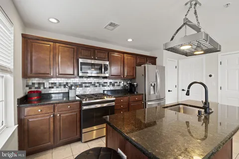 a kitchen with stainless steel appliances granite countertop a sink a stove top oven a refrigerator with granite countertops and cabinets