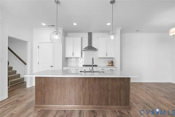 a large kitchen with kitchen island a stove a sink a refrigerator wooden floor and cabinets