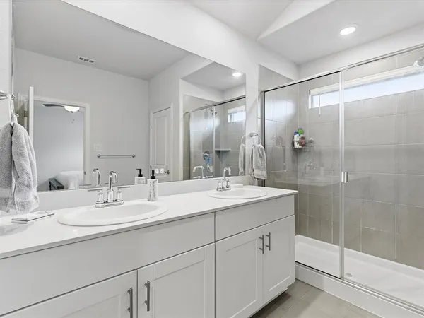 a bathroom with 2 sink shower and a mirror