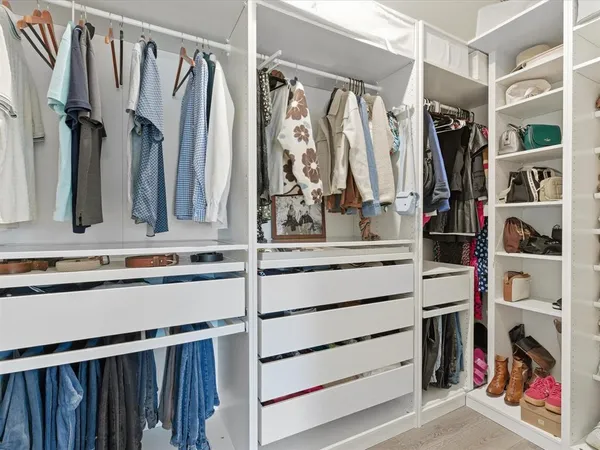 a view of walk in closet with clothes and shoes