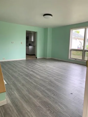 a view of empty room with a window and wooden floor