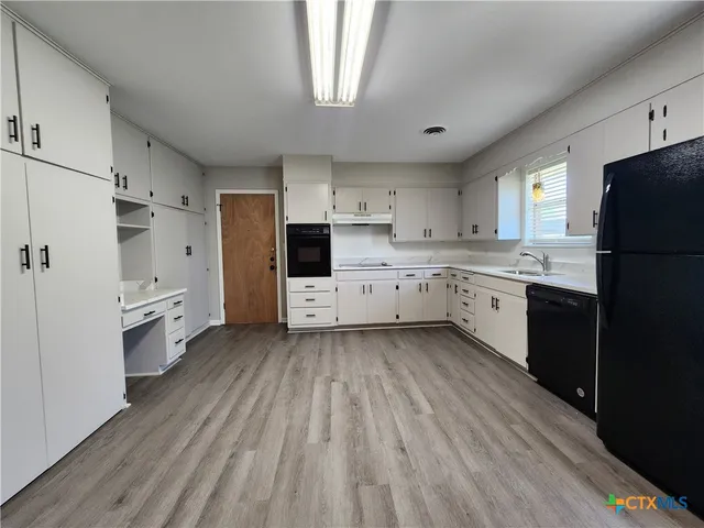 a kitchen with white cabinets and wooden floor