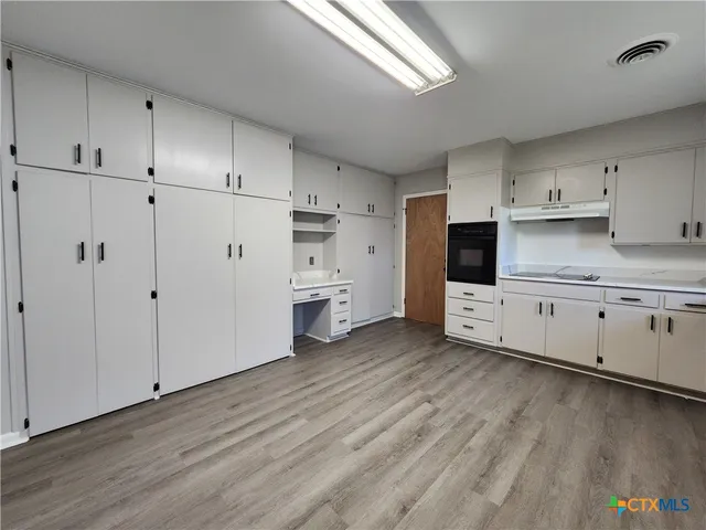 a kitchen with white cabinets and wooden floor