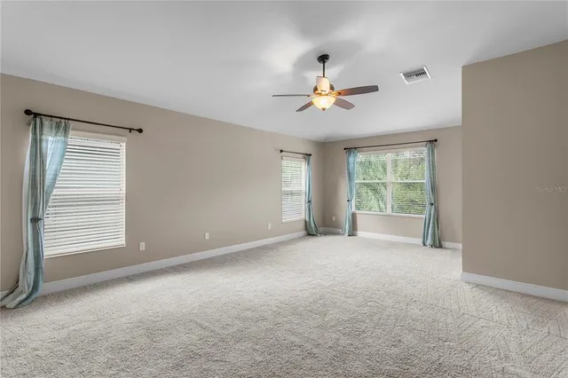 an empty room with windows and fan