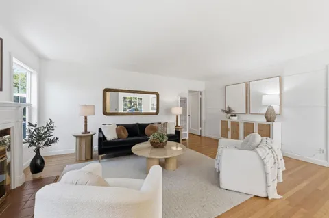 a living room with furniture and a large mirror with wooden floor
