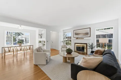 a living room with furniture two windows and a fireplace