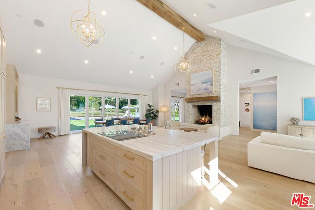 a large white kitchen with a stove a sink dishwasher and a fireplace with wooden floor