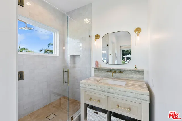 a bathroom with a granite countertop sink a mirror and shower