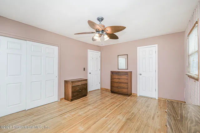 an empty room with wooden floor a ceiling fan and windows