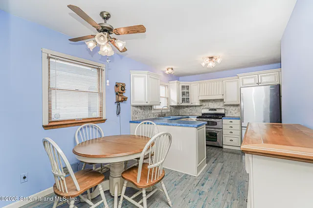 a kitchen with stainless steel appliances granite countertop a dining table chairs stove and refrigerator