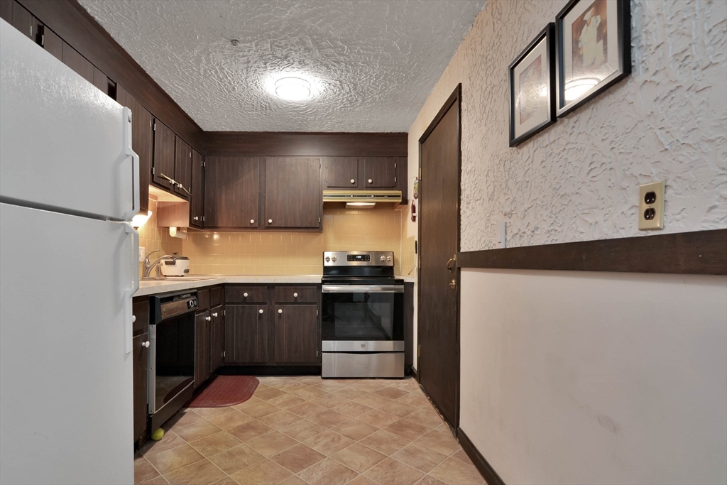 294 Codman Hill Road, Unit 33F Boxborough, MA 01719 - Photo 10 of 31 a kitchen with stainless steel appliances granite countertop a stove a sink and a refrigerator