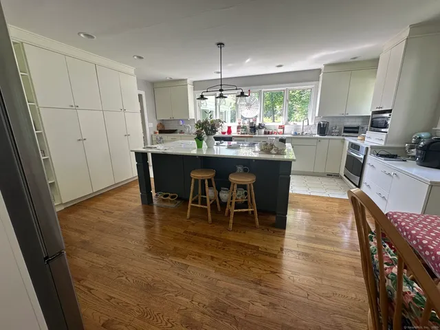 a dining hall with stainless steel appliances granite countertop wooden floor a dining table and chairs