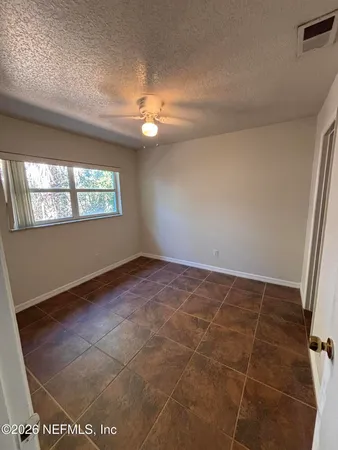 en empty room with windows and ceiling fan