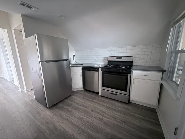 a kitchen with a refrigerator stove and wooden floor