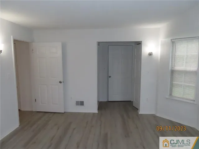 a view of an empty room with wooden floor and closet