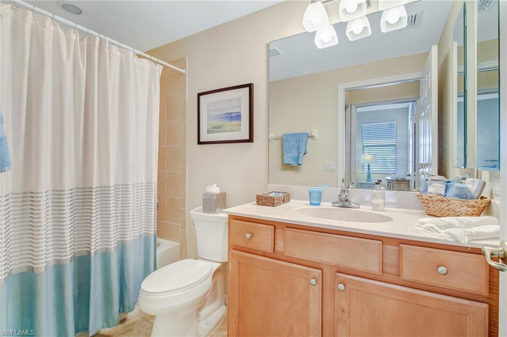 5706 Lago Villaggio Way Naples, FL 34104 - Photo 13 of 32 a bathroom with a sink a toilet and shower curtain