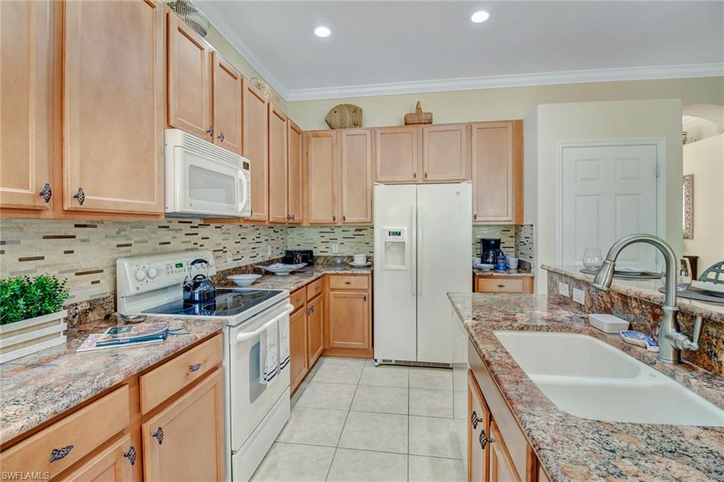 5706 Lago Villaggio Way Naples, FL 34104 - Photo 2 of 32 a kitchen with stainless steel appliances granite countertop a sink stove and refrigerator