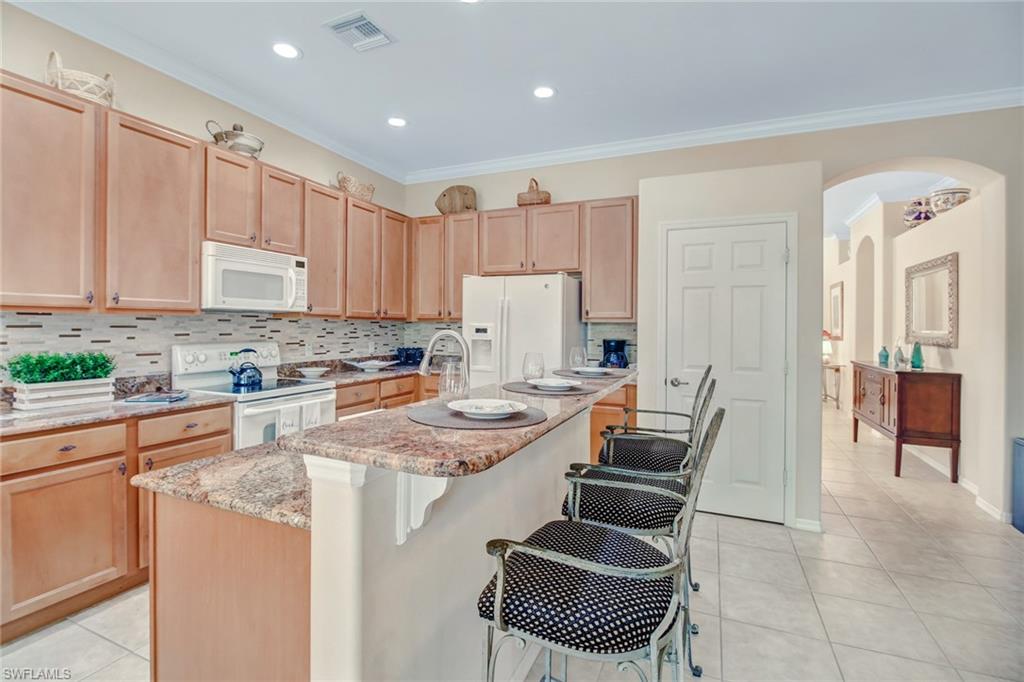 5706 Lago Villaggio Way Naples, FL 34104 - Photo 22 of 32 a kitchen with a refrigerator and white cabinets