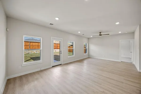 an empty room with wooden floor cabinet and windows