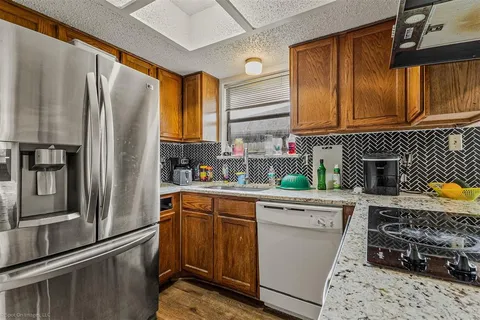 a kitchen with stainless steel appliances granite countertop a refrigerator a sink dishwasher stove with cabinets and wooden floor