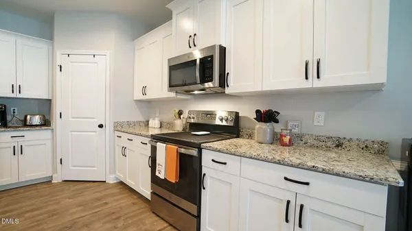 a kitchen with granite countertop white cabinets sink and stainless steel appliances