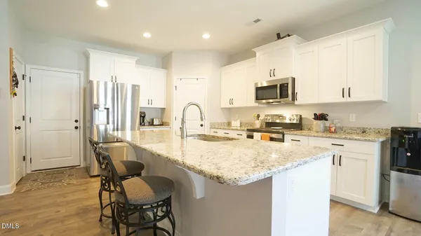 a kitchen with kitchen island granite countertop a stove top oven a sink a dining table and chairs with wooden floor