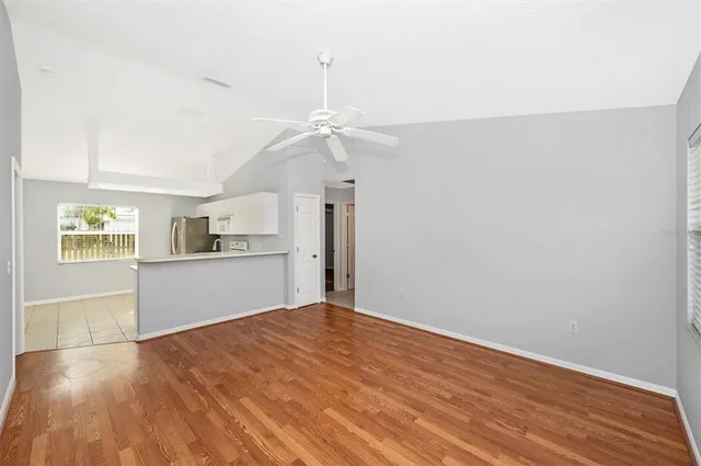 a view of kitchen and empty room with wooden floor