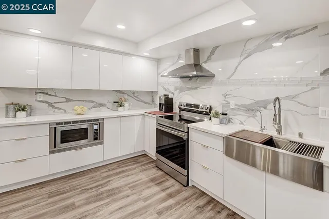 a kitchen with cabinets stainless steel appliances and wooden floor