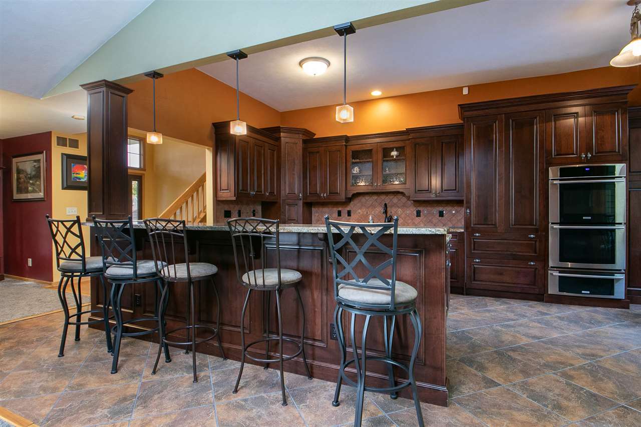 6820 Stone Cottage Road Rockford, IL 61114 - Photo 4 of 24 a kitchen with stainless steel appliances kitchen island granite countertop a table chairs sink and cabinets