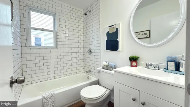 a bathroom with a sink a toilet a mirror a vanity a window and a shower