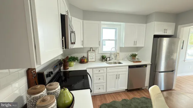 a kitchen with stainless steel appliances granite countertop a sink a refrigerator a stove and white cabinets