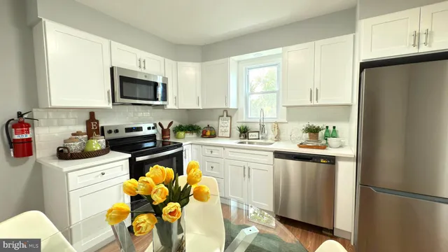 a kitchen with stainless steel appliances a stove a sink cabinets and a window
