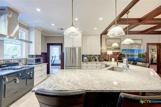 a large kitchen with kitchen island a large counter space a sink appliances and cabinets