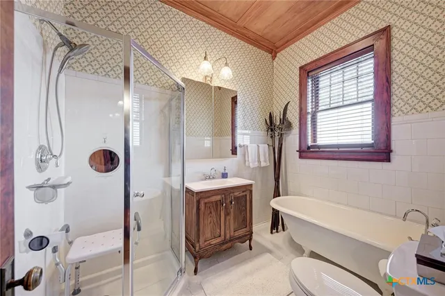 a bathroom with a tub sink mirror vanity and toilet