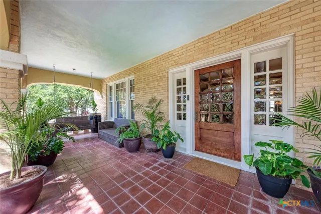 a view of a backyard with potted plants and floor to ceiling window and potted plants