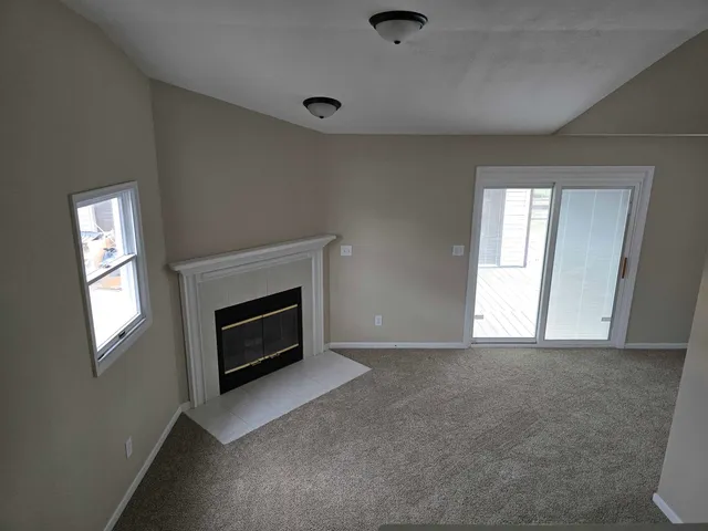 an empty room with windows and fireplace