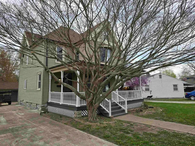 a view of a house with a large tree and a yard