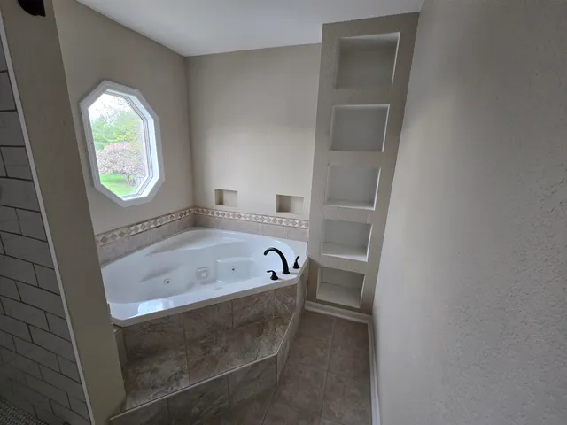 a bathroom with a tub a sink and a window